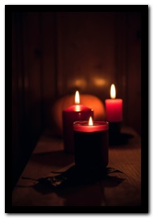 Picture of three red candles on a dark background communicating peace at a time of global intolerance and overconsumption. 