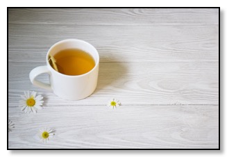 Picture of a cup of camomile tea on a table with flower heads, communicating support is available for dementia. 