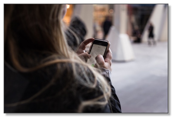 Picture of the back of a woman using a mobile phone, feeling lonely and needing help to have healthy relationships.