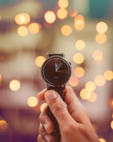 Image of a hand holding a wrist watch reflecting urgency of time in a quick-fix society.